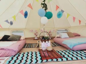 新加坡Glamping Kaki - Medium Bell Tent的帐篷内的两张床,配有气球和一张桌子