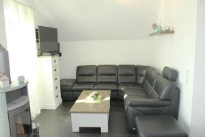 文迪施里茨5*Ferienwohnung Seeblick 4的客厅配有黑色真皮沙发和桌子