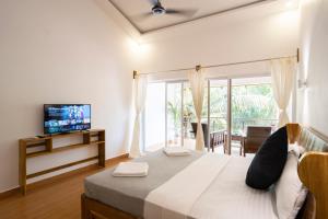 帕特南Crystall Goa Emerald Edition的一间卧室设有一张床、电视和窗户