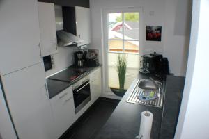 文迪施里茨5*Ferienwohnung Seeblick 4的厨房配有白色橱柜、水槽和窗户。