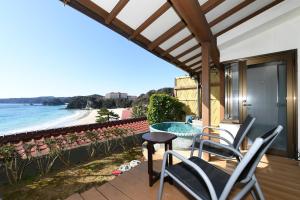 下田下田大和旅馆的一个带椅子和桌子的庭院,享有海滩美景