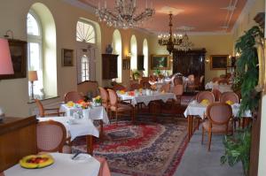 拉特诺福斯特霍夫酒店的餐厅配有白色的桌椅和吊灯