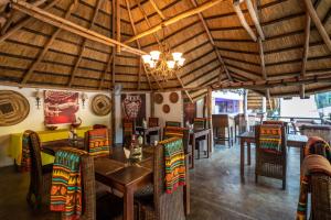 利文斯顿Ngoma Zanga Lodge的一间带桌椅和吊灯的餐厅