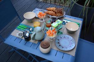 拉罗谢尔Chambres d'hôtes Le Clos Bleu的一张桌子,上面摆放着蓝色椅子上的食品和饮料