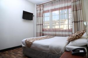 内罗毕Hotel Embassy的一间卧室设有一张床和一个大窗户