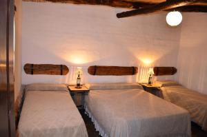 Angastaco芬卡埃尔卡门乡村民宿的一间卧室配有两张床,墙上有两盏灯