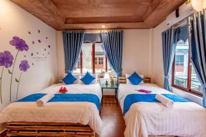 宁平Khai Yen Tam Coc Hostel的配有蓝色窗帘的客房内的两张床