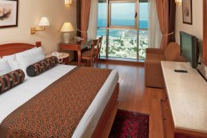 海法Crowne Plaza Haifa, an IHG Hotel的酒店客房配有一张床、一张书桌和一台电视。
