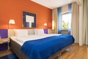 诺尔雪平ProfilHotels President的一间卧室配有一张带橙色墙壁的大床