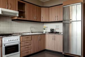 贝鲁特拉霍亚公寓的厨房配有木制橱柜和不锈钢冰箱。