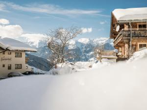 齐勒河谷采尔Hanserhof的一座被雪覆盖的建筑,背景是群山