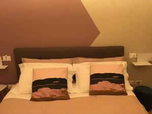 代森扎诺-德尔加达Hotel Moniga的一张带白色枕头和棕色床头板的床