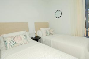 卡莱利亚德帕拉弗鲁赫尔Luxury Central Apartments, Illa Blanca, Calella的墙上挂钟的房间里设有两张床