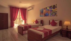 尼甘布Bohemian Hotel - Negombo的一间卧室设有两张床,墙上挂着一幅画