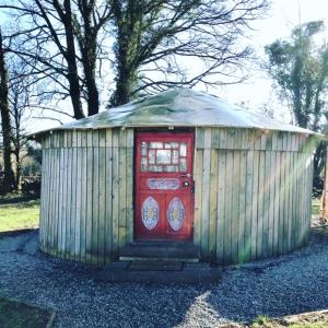 基尔肯尼McClure Yurt at Carrigeen Glamping的院子里有红色门的小棚子