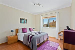 卡巴纳斯·德·塔维拉OPomar at Cabanas by Cara Rentals的一间卧室配有一张带紫色枕头的床和窗户。
