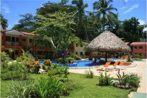 科克Cocomarindo Condo #72的一个带椅子和草伞的游泳池的度假酒店