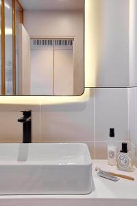 巴黎Tinah Paris, Réaumur - Montorgeuil的浴室设有白色水槽和镜子
