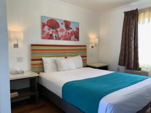 卡宾特里拉沙地礁旅馆的一间卧室配有一张大床和色彩缤纷的床头板