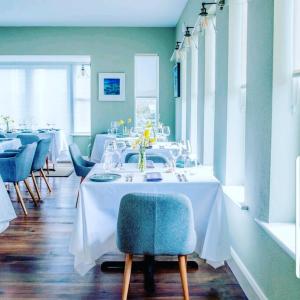 杜林Oar restaurant and Rooms的一间配备有白色桌子和蓝色椅子的用餐室
