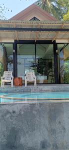班柯木慕客塔马林德度假村的两个白色椅子坐在一个带游泳池的凉亭下
