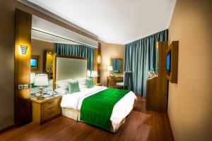 吉达Jeddah Grand Hotel的一间卧室配有一张带绿毯的大床