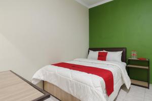 加拉旺RedDoorz near Cikampek Mall Karawang的一间卧室配有一张带绿色墙壁的床