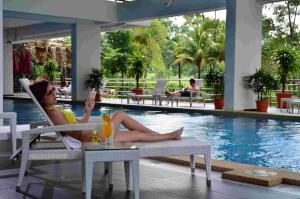 新山阿曼萨丽公寓度假酒店的坐在游泳池旁椅子上的女人