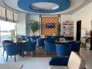 阿吉曼Hala Inn Hotel Apartments - BAITHANS的餐厅设有蓝色的桌椅和蓝色的天花板
