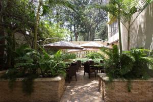 内罗毕Reata Apartment Hotel的一个带桌椅、植物和遮阳伞的庭院
