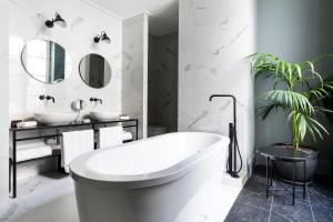 巴塞罗那Maldà Singular Hotel的白色的浴室设有浴缸和植物
