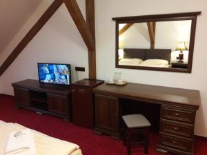 新比斯特日采福格酒店的一间带镜子的卧室和一张带电视的书桌