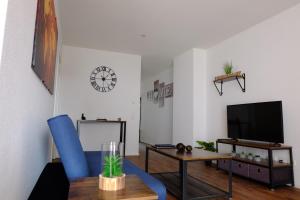 莱茵豪森Sweet Park Appartements的客厅配有蓝色椅子和电视