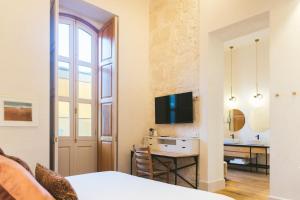 大加那利岛拉斯帕尔马斯VEINTIUNO Emblematic Hotels - Adults Only的一间客厅,客厅内配有一张桌子和一台电视机
