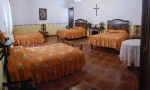 San Lorenzo SoltepecEx-Hacienda San Buenaventura的客房设有四张床、橙色床单和桌子