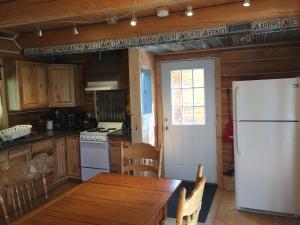 CarcrossCabins Over Crag Lake的厨房配有木桌和白色冰箱。