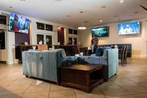 珀斯金合欢树林汽车旅馆的餐厅设有蓝色的沙发、桌子和电视