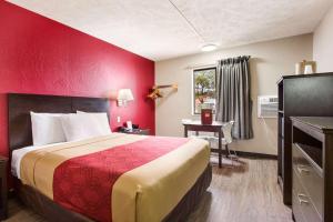 奥拉西Red Lion Inn & Suites Olathe Kansas City的酒店客房,设有一张红色墙壁的床