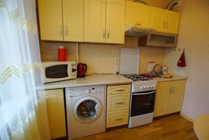 卡缅斯科耶Квартира的厨房配有黄色橱柜、炉灶和微波炉。