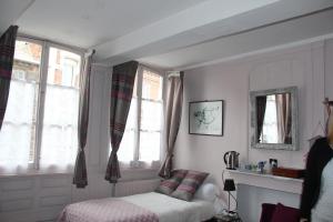 阿布维尔Les Capucines的一间卧室设有一张床和两个窗户。