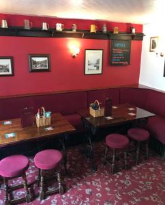 斯泰兹The Royal George Staithes的餐厅设有红色的墙壁和两张桌子及凳子
