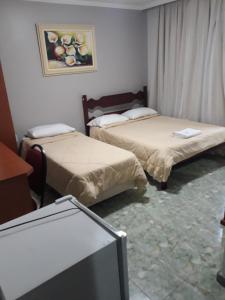 马卡埃Hotel Nolasco的一间设有两张床和一台电视的房间