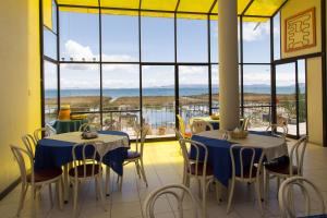 Ichu迪迪喀喀湖游艇酒店的带大窗户的客房内的2张桌子和椅子