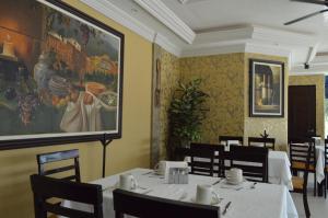 伊达尔戈州波萨里卡hotel villa magna poza rica的用餐室配有桌椅,墙上挂有绘画作品