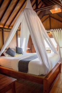 姆杜克巴厘岛拉哈优民宿的一间卧室配有一张带蚊帐的床