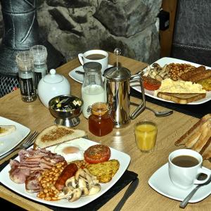 兰贝里斯Alpine Lodge Guest House的一张木桌,上面放着早餐食品和咖啡盘