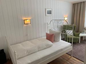 奥斯特巴特宁哈根里希特旅馆的一张带两把椅子和一张桌子的白色床