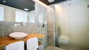 玛里纳Sky Beach Aparthotel的一间带水槽和玻璃淋浴的浴室