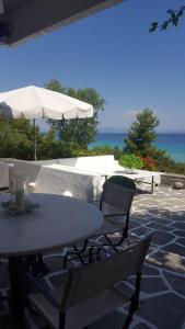 卡利塞亚-豪客迪克斯A beautiful beachfront maisonette的一张桌子和椅子,配有雨伞和大海