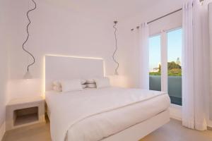皮尔戈斯圣托里尼艺术酒店的白色的卧室设有白色的床和窗户。